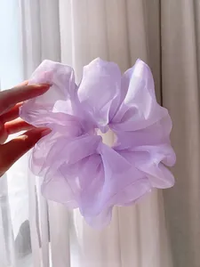 Macro shot of purple organza scrunchie featuring pleated texture and translucent fabric