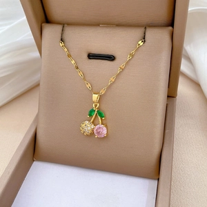 Macro shot of gold cherry necklace with pink gemstone and micro-pave crystals in box