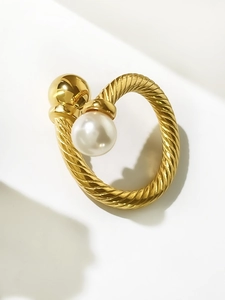 Close-up of twisted 18K gold titanium steel ring with white pearl and metal bead