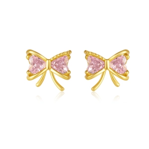 Close-up of golden bow earrings with pink heart-shaped crystal and mirror reflection