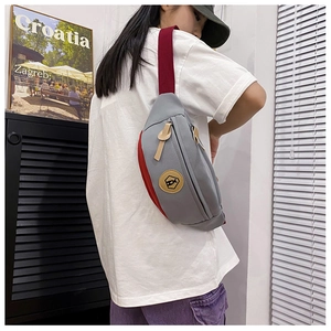 Detail of adjustable red strap and canvas splicing on a grey crossbody chest bag