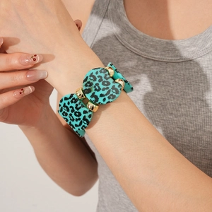 Close-up of wide leopard print bracelet with blue acrylic panels and gold metal beads