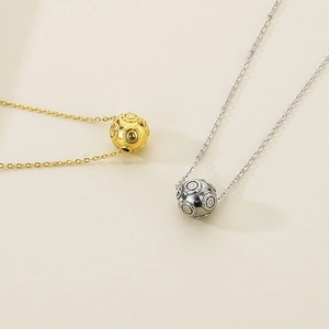 Detail of gold and silver hollow sphere pendants with fine circular texture on chains
