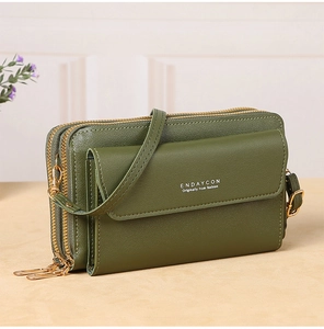 Close-up of a dark green crossbody phone bag with three zippers and gold hardware