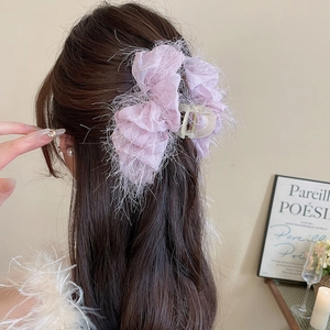 Vue détaillée de l'arrière d'une pince à cheveux rose clair effet plume sur cheveux bruns