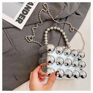 Close-up of a silver acrylic clutch with 3D spherical texture and metal bead chains