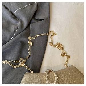 Detail of glitter evening clutch bag with gold chain and rhinestone buckle on grey fabric