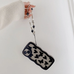 Detail of beaded phone strap with white pearls and dice pendant on black butterfly case