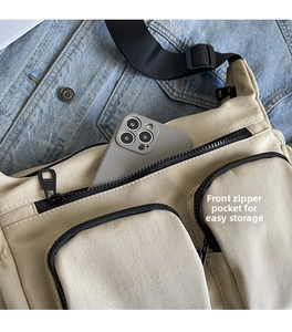 Detail of off-white canvas crossbody bag with multiple zipper pockets on denim background