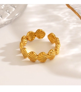 Detail of a golden shell-shaped open ring with textured finish on a white background