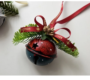 Detailed view of metal Christmas bells with star cutouts, pine needles and a festive bow