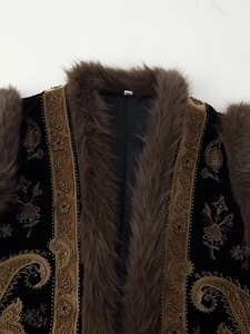 Detailed close-up of ethnic beaded embroidery and brown fur collar on a black velvet vest