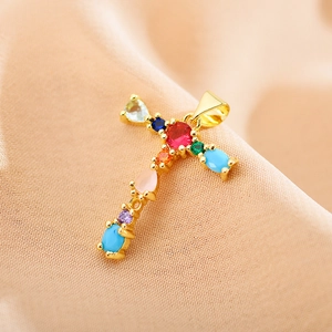 Macro shot of a gold cross pendant with colorful zircon stones on silk background