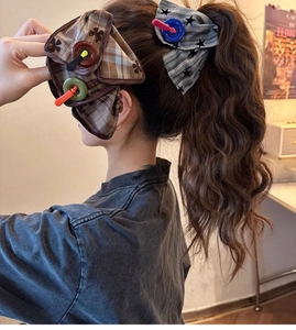 Detail of large fabric bow hair claws with plaid and stripe patterns on a ponytail