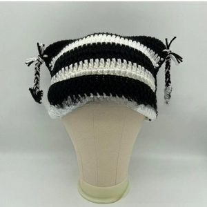 Close-up of black and white striped knit cat ear hat with decorative braided tassel ropes