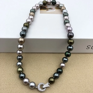 Macro detail of multi-colored pearls showing peacock green luster and diamond clasp