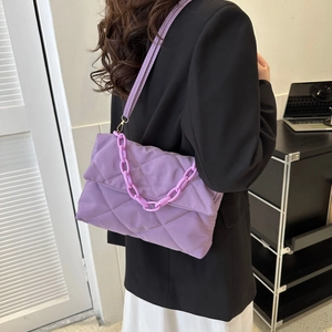 Detail of purple quilted shoulder bag featuring chunky plastic chain and glossy texture