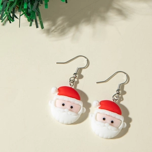 Gros plan de boucles d'oreilles Père Noël en résine avec crochets argentés sur beige
