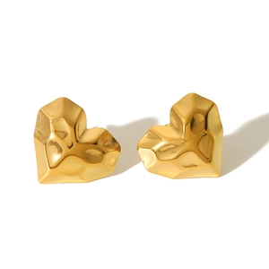 Macro detail of gold heart earrings with irregular hammered texture and metallic shine