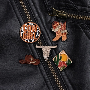 Close-up of five western cowboy enamel pins displayed on a black leather jacket