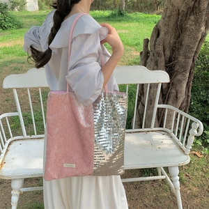 Close-up of pink velvet and silver sequin patchwork tote bag worn by a model outdoors