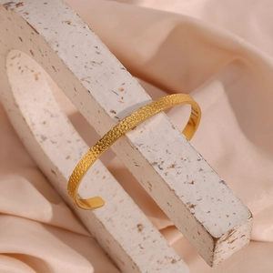Detailed view of 18K gold plated stainless steel cuff bracelet with hammered texture