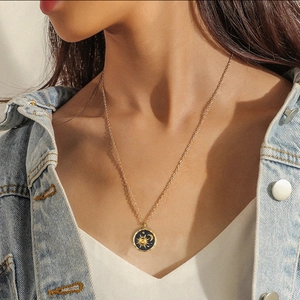 Detail of sun and moon pendant necklace worn by a model in casual denim jacket