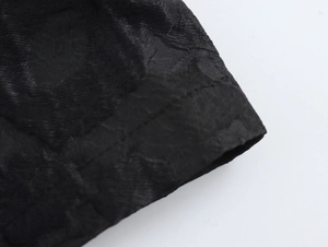 Macro shot of black textured jacquard fabric detailing stitching on long coat sleeve