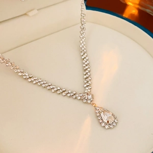 Detail der silbernen Tropfenhalskette mit Strass-Y-Design in einer weißen Schmuckschatulle