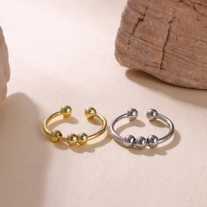 Macro shot of 18k gold and silver anxiety rings with sliding beads on a minimalist stone