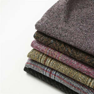 Close-up of stacked colorful wool-like boucle fabrics showing detailed knit textures