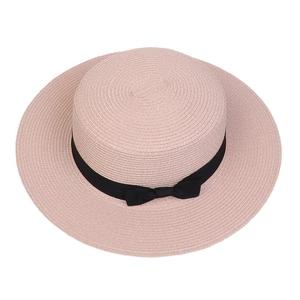 Top view of pink straw hat with a black ribbon bow showing detailed woven texture