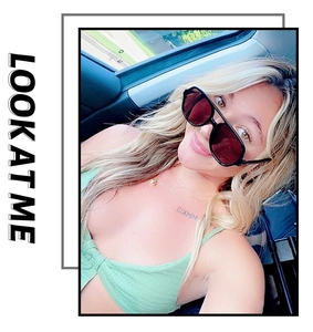 Fashionable black square pilot sunglasses with dark lenses worn by a model in a car