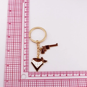 Detail of golden cowboy keychain with brown revolver and white star bandana charms