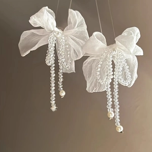 Detail of floral earrings featuring sheer bow, beaded tassels and elegant pearls