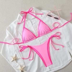 Detailed view of pink string bikini with side-tie bottoms and beach holiday accessories