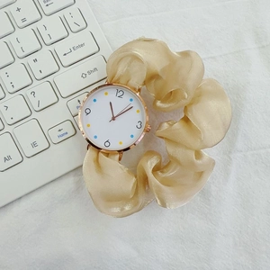 Detailed macro view of gold watch dial with colorful markers and beige silk ribbon strap