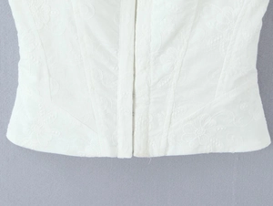Close-up of white floral embroidery details and hook-and-eye closure on corset top