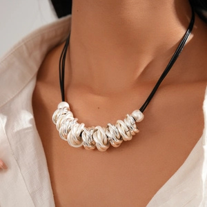 Detail of layered leather cord necklace with geometric silver rings worn by model