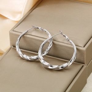 Silver twisted C-shape stainless steel hoop earrings on a luxury jewelry gift box