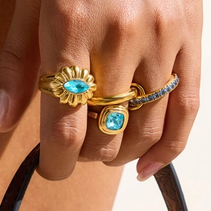 Detail of three gold rings with blue zircons featuring marquise and square cut stones