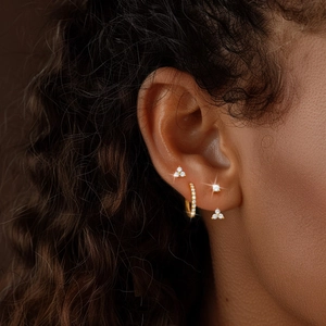 Macro shot of gold-plated silver earrings set with zircon stones on a female model's ear