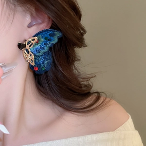 Close-up of blue embroidered butterfly earring with crystal rhinestones on model