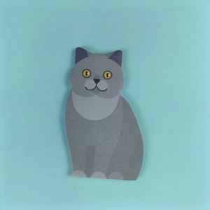 Close-up of a cute grey sitting cat shaped sticky note on a solid light blue background