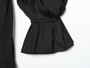 Vue détaillée d'une manche de robe noire en soie avec un design élégant à volants