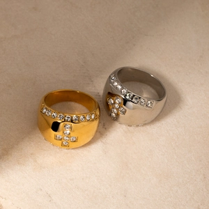 Detailed close-up of 18k gold and silver cross rings with sparkling crystal inlay
