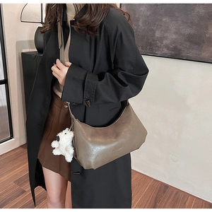 Detail view of khaki PU leather crossbody bag with cute plush bear charm on a model