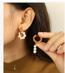 Détail de boucles d'oreilles dorées asymétriques avec perles blanches de style moderne