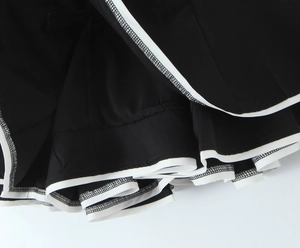 Close-up of black fabric with white contrast piping and detailed hem stitching finish