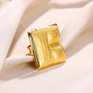Detailed macro view of gold-tone square ring with vertical stripes and hammered texture